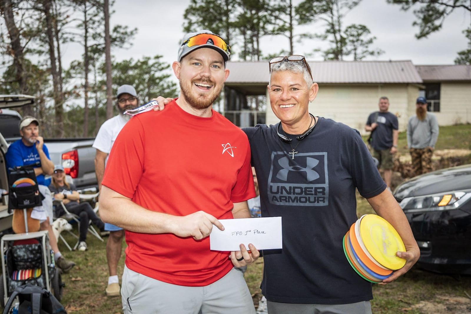 Two players smile with a prize envelope and a stack of discs after the Kickoff.